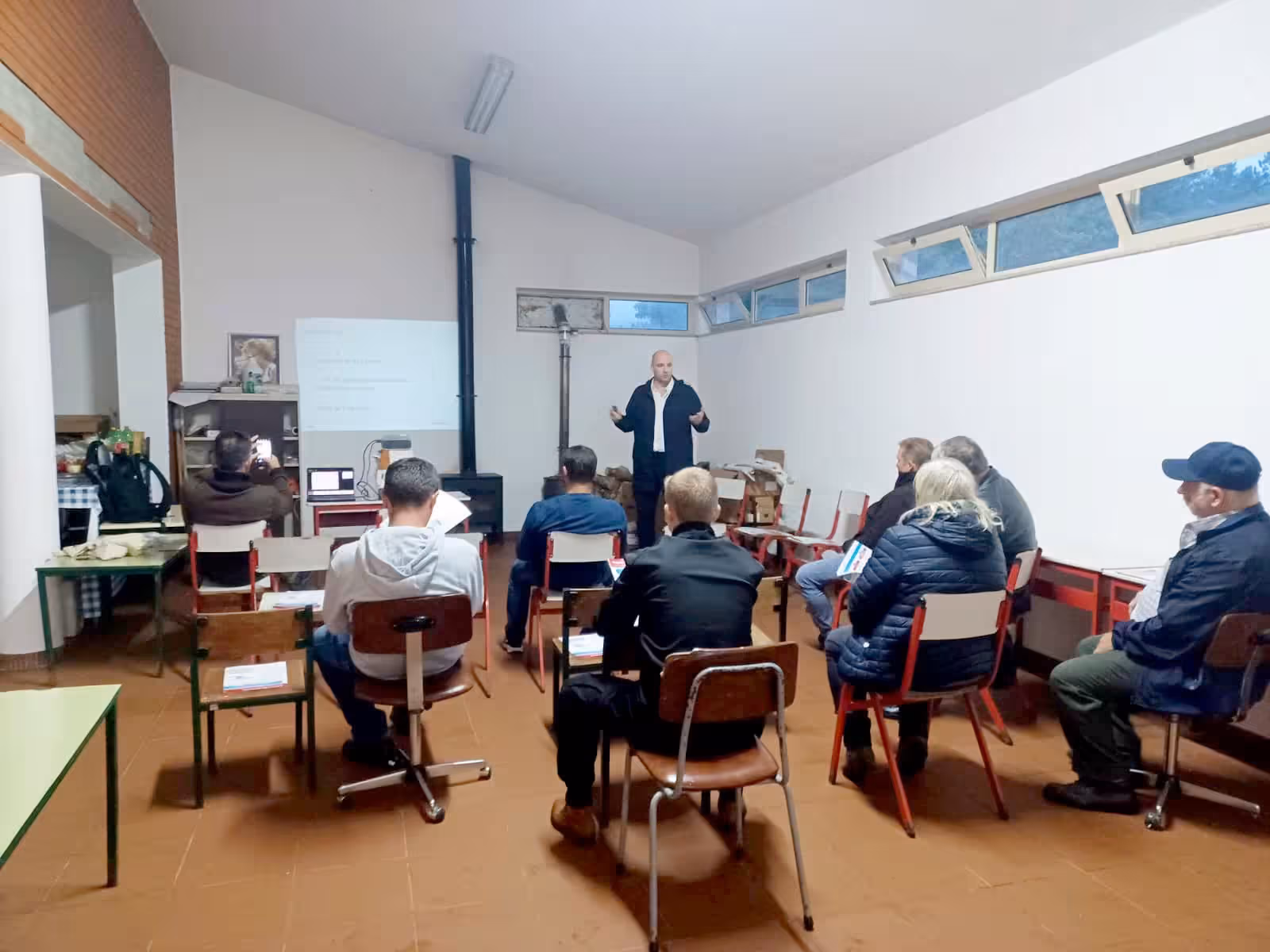 Thomas Gaultier facilitating a small community meeting in a village hall in northern Portugal, residents seated in a circle around him