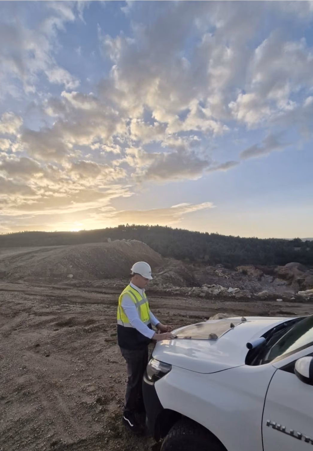 Thomas Gaultier in hard hat and high-visibility vest beside a pick-up at a mine site at sunset